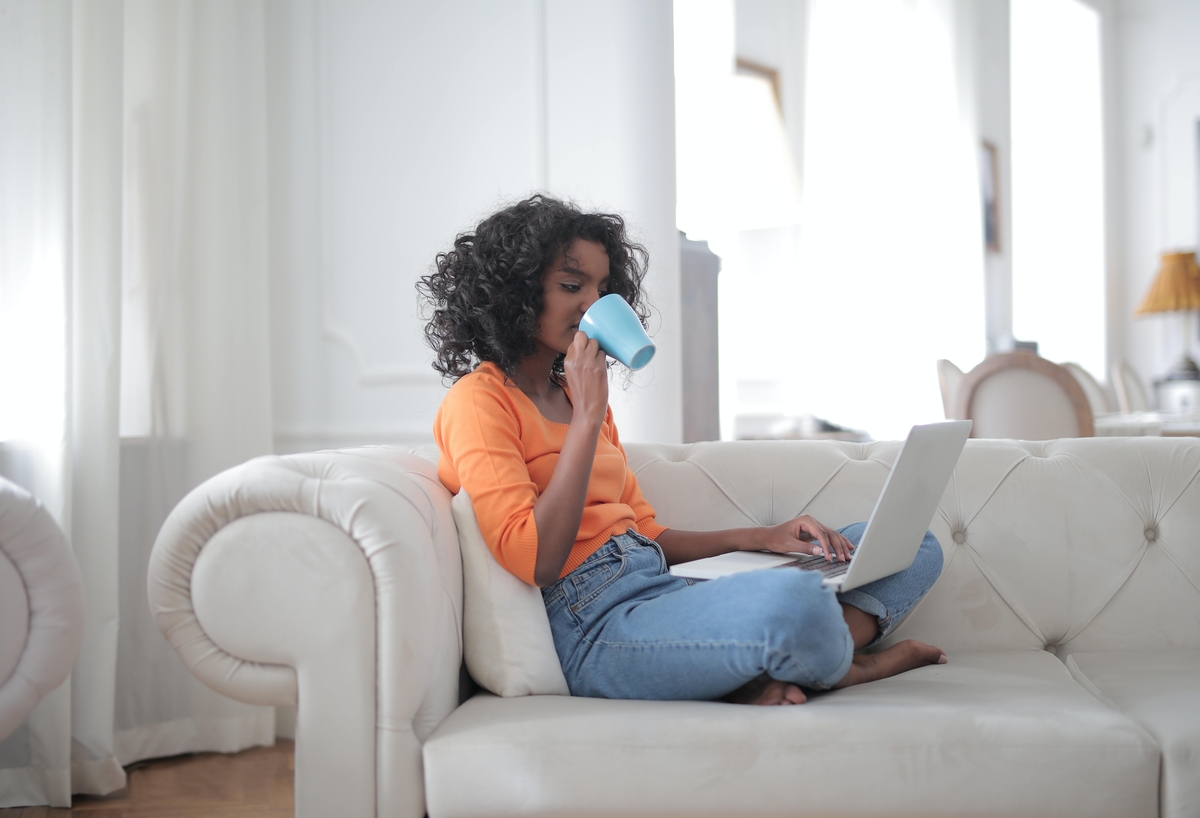 Woman using her computer in the kitchen counter drinking a glass of milk